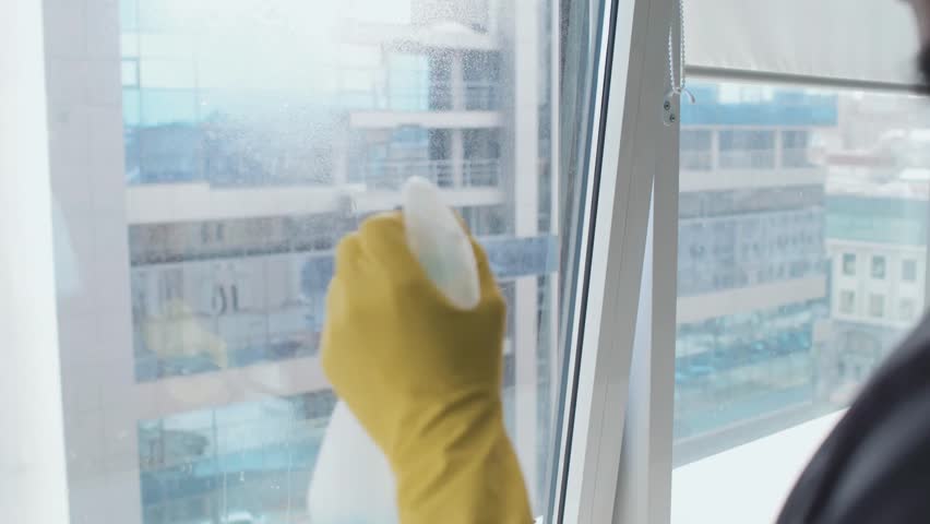 Selective-focus of an African-American man working in a cleaning service, spraying disinfectant. Professional janitorial work, sanitation, and workplace hygiene captured in detail.