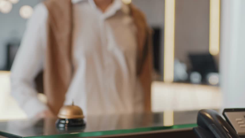 Selective-focus slow-motion close-up of an unrecognizable receptionist handing a key card to a hotel guest, capturing professional service and hospitality.