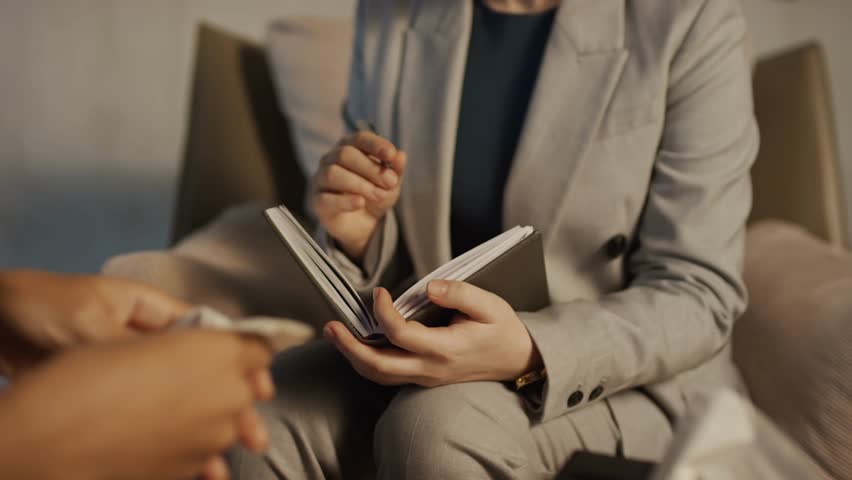 Selective-focus close-up of an unrecognizable female therapist handing a clipboard and pen to a patient, illustrating support, guidance, and professional consultation.