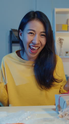 Vertical Screen : Happy young Asia businesswoman looking at camera selling introduce product to client video live streaming in online shop  marketplace at night. Small business owner, market delivery.
