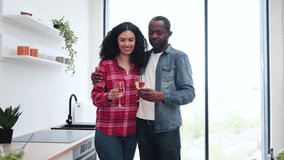 A diverse couple shares a toast with wine glasses in a modern kitchen setting, celebrating a special moment. - Powered by Shutterstock - Get 15% off with code: PIKWIZARD15
