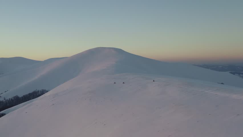 Aerial view of motorbikes on snowy mountains with riders carving fresh tracks