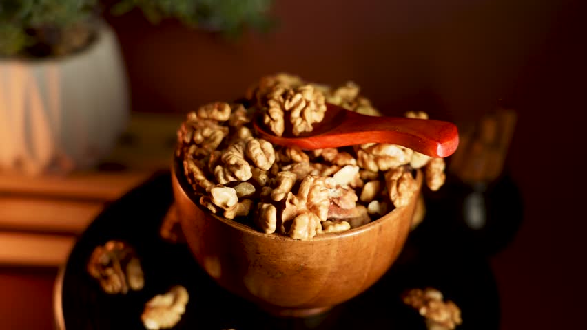 Peeled walnuts placed in a wooden bowl with a red scoop