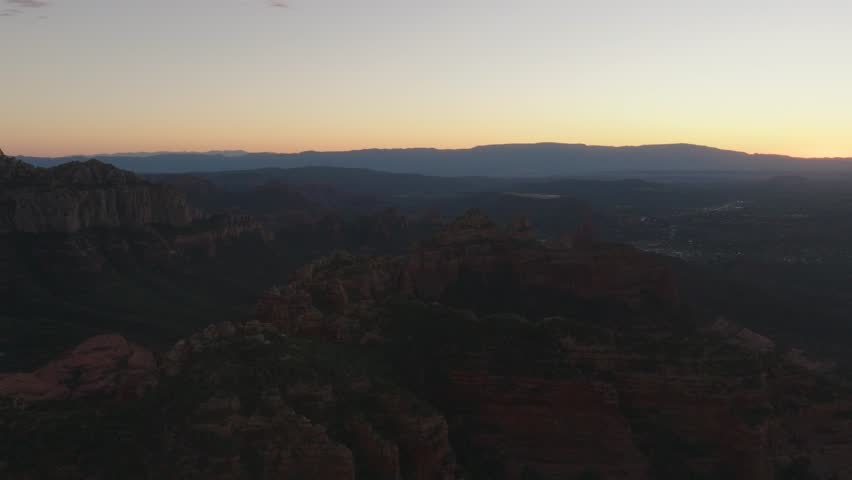 Wide Aerial Drone Landscape of Sedona Arizona Red Rocks and Valley at Twilight with Distant City Lights and Mountain Layers