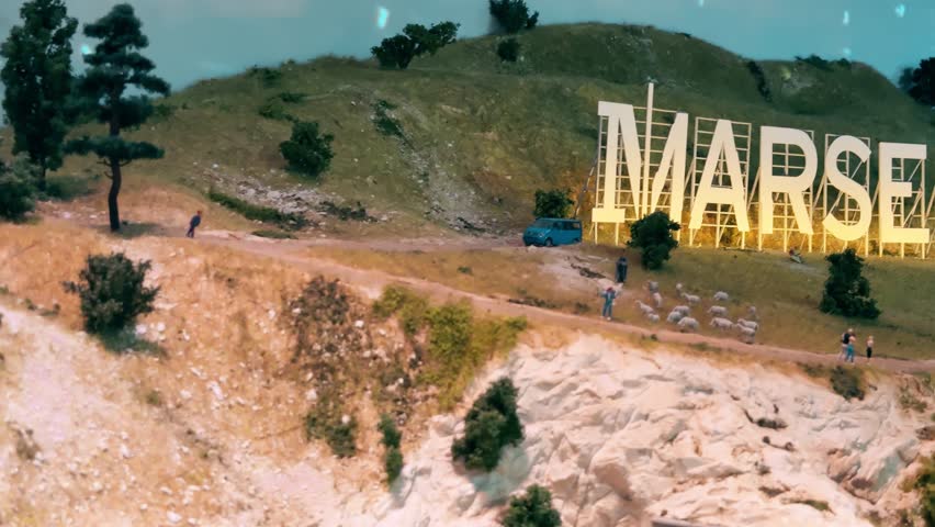 Miniature Marseille hillside sign with glowing letters at sunset