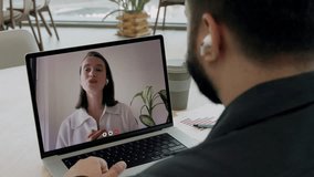Indian businessman with headphones listens to woman financial counselor on video call in office. Young entrepreneur discusses strategy of company growth remotely via laptop indoors - Powered by Shutterstock - Get 15% off with code: PIKWIZARD15