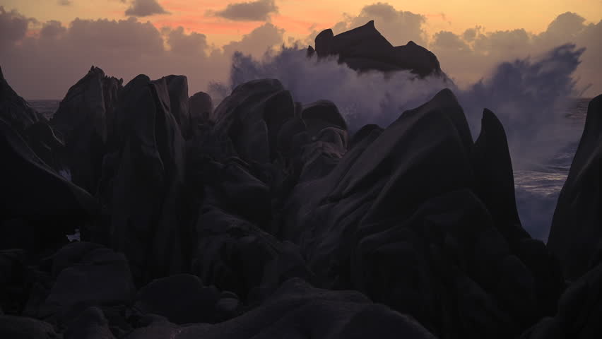 Dramatic Twilight View of Granite Rocks in Sardinia as Powerful Storm Waves Crash and Create Misty Sea Spray Along the Rugged Coastline