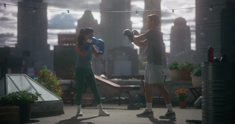 Young Woman Practices Boxing Drills With a Male Partner on a Rooftop Workout Area, Using Light Mitt Work for Exercise, Heart Health, Stress Relief, and Calm, Mindful Everyday Fitness Training.