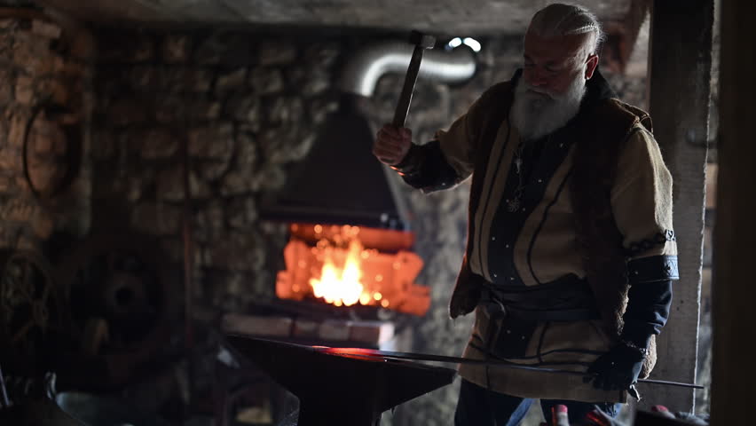 A Viking blacksmith with a white beard and braided hair works intently at a forge, hammering glowing metal on an anvil, with flames flickering in the background of a stone workshop cinematic slow
