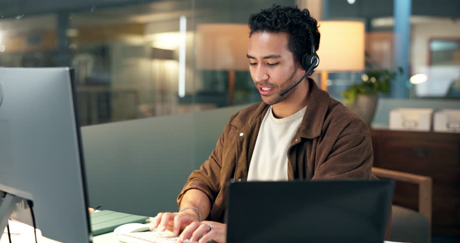 Help desk, contact us and man typing on computer for IT feedback, assistance or advice at night. Tech support, smile and person speaking with technician for troubleshooting in call center on overtime