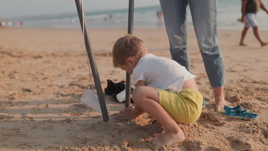 Young boy playing with sand on a sunny beach