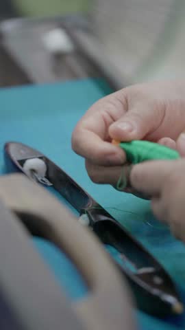Close up slow motion of a hand pushing the weaving loom shuttle while weaving blue silk fabric on traditional loom in Thailand Artisan textile threads craftsmanship motion Vertical