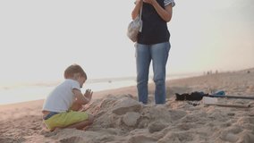 Little boy building a sandcastle with his mother on the beach - Powered by Shutterstock - Get 15% off with code: PIKWIZARD15