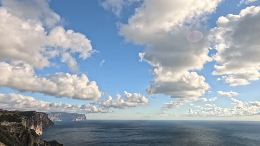 Sea, cliffs, clouds a beautiful seascape with dramatic cliffs meeting the calm blue sea under a vast sky filled with white clouds