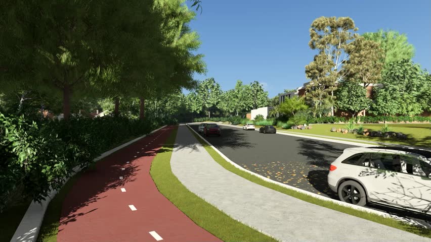 A roadside park with trees and a walking path. Cars are driving on the road. The sky is blue and clear.