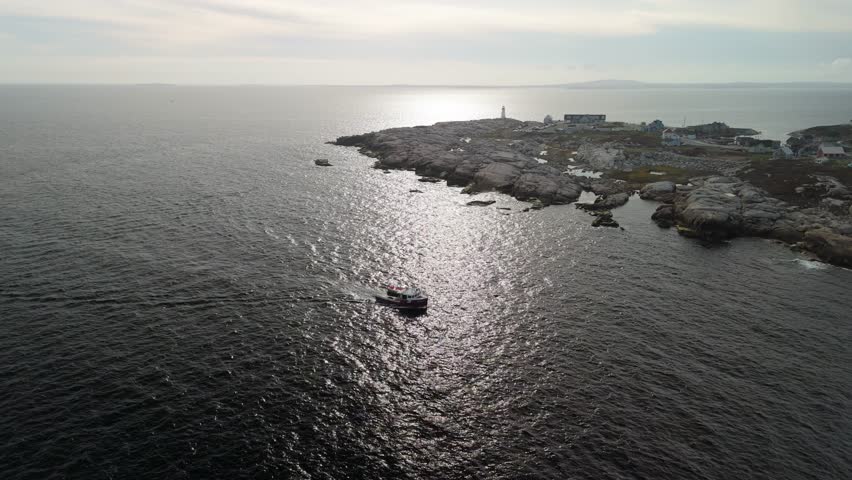 Aerial View Showing Lobster Fishermen Working From A Small Boat Near Peggys Cove In Halifax, Nova Scotia, With The Rugged Atlantic Ocean Surrounding Them, Historic Coastal Homes Along The Harbor