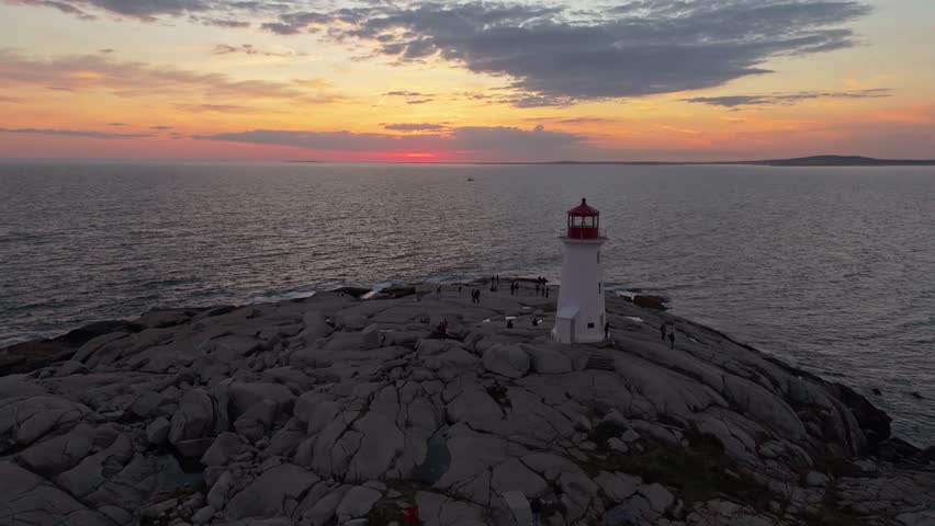Beautiful Aerial View Capturing Iconic Peggys Cove Lighthouse Near Halifax,Nova Scotia, Illuminated By Soft Sunset Colors, With Its Reflection Visible On Smooth Granite Rocks And The Rugged Atlantic