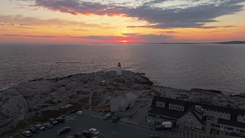 Aerial View Showing Famous Peggys Cove Lighthouse Near Halifax, Nova Scotia, Standing On Harsh Granite Rocks Under Glowing Sunset Skies, With Soft Reflections On The Shoreline And The Atlantic Ocean