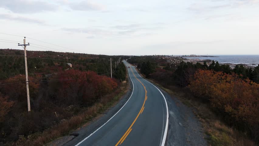 Aerial View Showing A Grey Car Traveling Along An Empty Coastal Road Near Peggys Cove In Halifax, Nova Scotia, With Scenic Atlantic Ocean Views And A Summer Road Trip Atmosphere Creating A Peaceful
