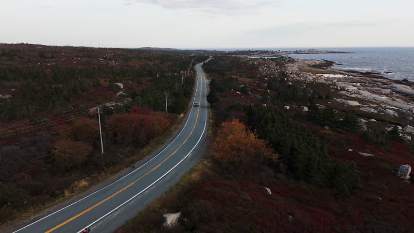 Aerial View Capturing A Grey Car Moving Along A Quiet Road Beside The Atlantic Near Peggys Cove In Halifax, Nova Scotia, With Bright Summer Light And Open Ocean Scenery Adding A Sense Of Freedom 