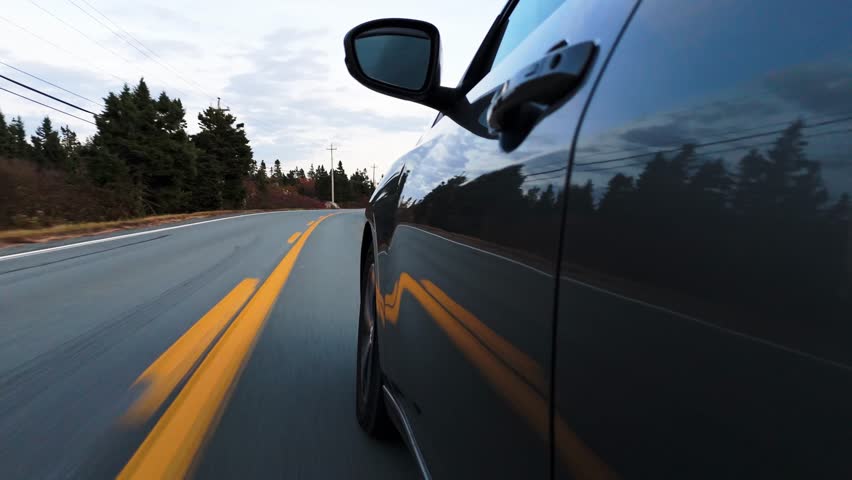 Low Angle POV Showing A Sports Car Wheel Spinning Along A Country Road At Sunset Near Peggys Cove In Halifax, Nova Scotia, With Warm Light On The Asphalt And Coastal Air Creating A Dynamic Automotive