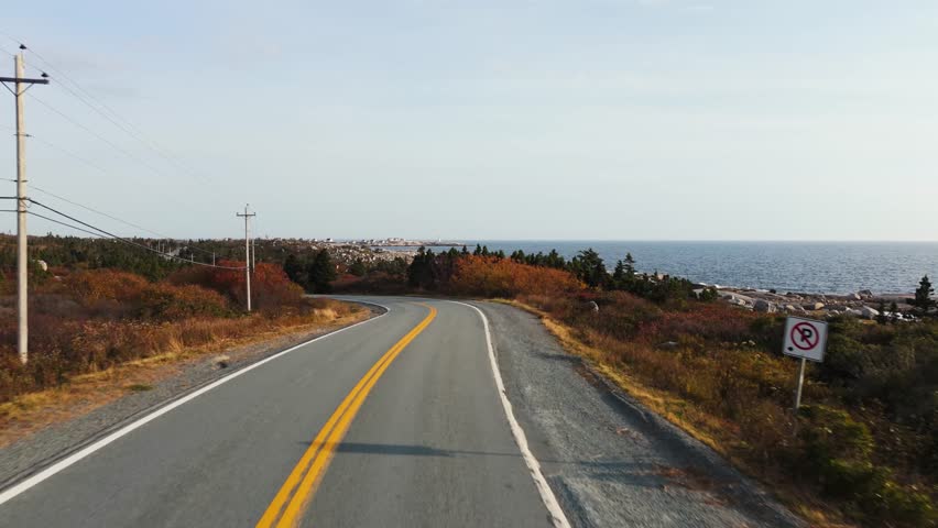 Aerial Footage Showing A Grey Car Traveling Along A Coastal Highway Near Peggys Cove In Halifax,Nova Scotia, With Rocky Shores And Atlantic Ocean Breeze Creating A Classic Summer Road Trip Experience