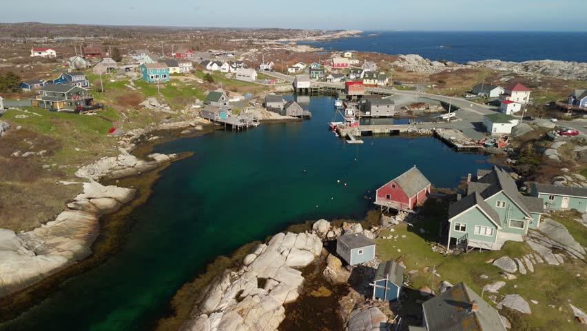 Cinematic Aerial View Of Peggys Cove In Halifax, Nova Scotia, Showing Colorful Lobster Boats, Charming Wooden Homes, Quiet Harbor Waters, And The Famous Lighthouse Resting On Massive Granite Rocks 