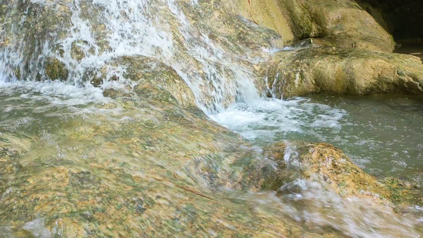 natural waterfall in the mountains. Water flows over limestone rocks