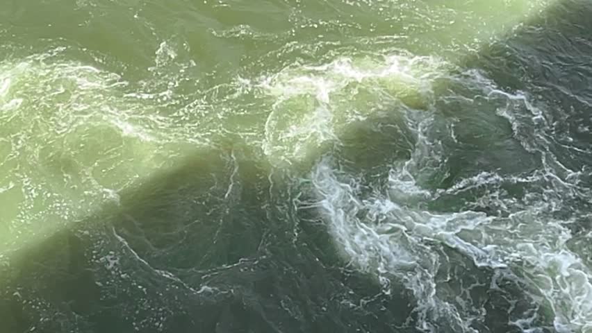 The water flowing from the dam gate creates small swirling ripples that float gently downstream