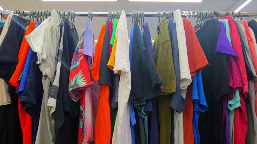 A well-organized retail clothing rack features a vibrant array of shirts, t-shirts, and tops in various colors and patterns. Perfect for fashion, retail, and wardrobe inspiration.