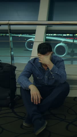exhausted man at airport, frustrated traveler rests on airport ground after delays and fatigue