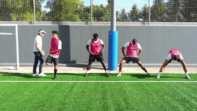 Male football team with coach doing warm up exercises on artificial turf. Multi ethnic players preparing for a match on a sunny day - Powered by Shutterstock - Get 15% off with code: PIKWIZARD15