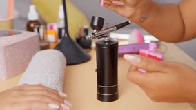 Professional manicurist pouring pink nail polish into a portable airbrush machine during a beauty treatment session in a modern salon - Powered by Shutterstock - Get 15% off with code: PIKWIZARD15