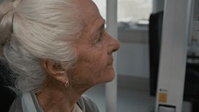 Side view close up shot of white haired senior woman looking into automated phoropter during eye exam with modern diagnostic machine in clinic, copy space - Powered by Shutterstock - Get 15% off with code: PIKWIZARD15