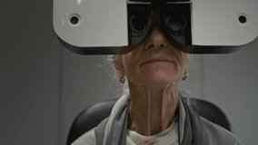 Minimal front view shot of senior woman looking into phoropter during eye exam and using modern automated diagnostics machine in clinic, copy space - Powered by Shutterstock - Get 15% off with code: PIKWIZARD15