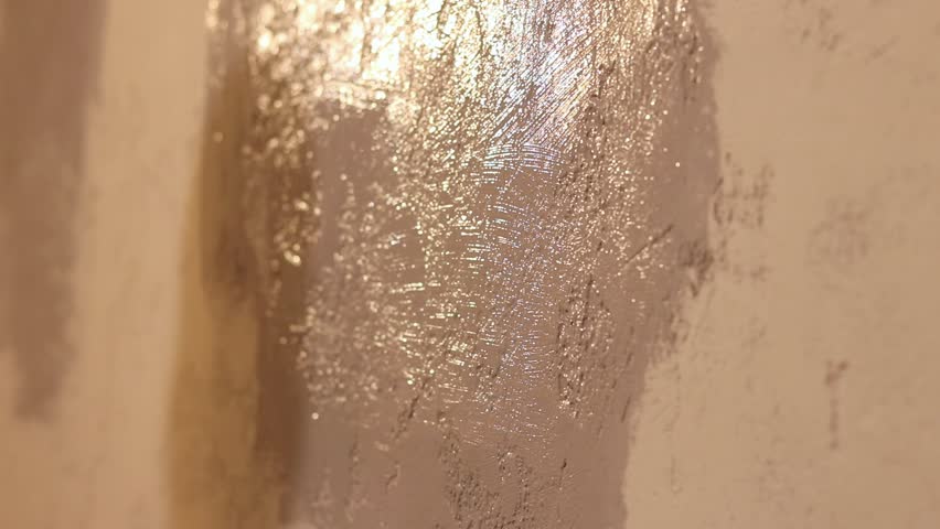 Painting a wall indoors, selective focus. Repainting a wall, hand with a wide brush close-up. Repair and painting work. Close-up of a woman's hand with a brush painting a wall with gray paint