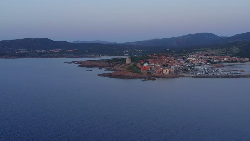 Aerial drone view of Castelsardo and Isola Rossa seaside town at sunset with a marina along the azure coastline of Sardinia, Italy