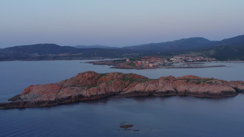 Aerial drone view of Castelsardo and Isola Rossa seaside town at sunset with a marina along the azure coastline of Sardinia, Italy