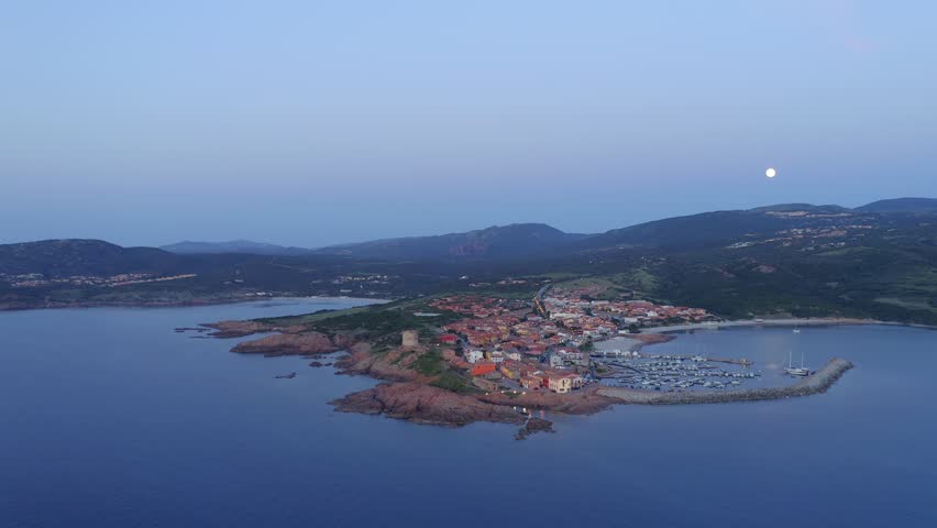 Aerial drone view of Castelsardo and Isola Rossa seaside town at sunset with a marina along the azure coastline of Sardinia, Italy