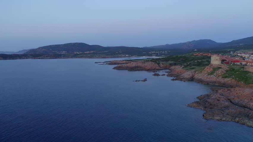 Aerial drone view of Castelsardo and Isola Rossa seaside town at sunset with a marina along the azure coastline of Sardinia, Italy