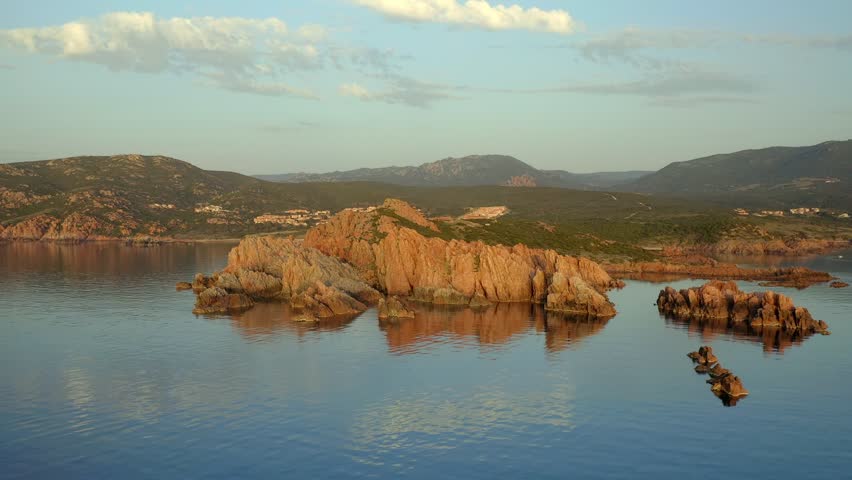 Drone aerial view of Punta Canneddi red rock landscape in Isola Rossa beach region of Sardinia, Italy at sunset