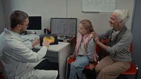 Side view shot of male doctor as ophthalmologist consulting senior woman with child in eye clinic and pointing at images on digital tablet screen - Powered by Shutterstock - Get 15% off with code: PIKWIZARD15