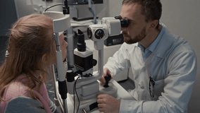 Medium shot of smiling male doctor giving candy to girl after eye exam with slit lamp in ophthalmology clinic - Powered by Shutterstock - Get 15% off with code: PIKWIZARD15