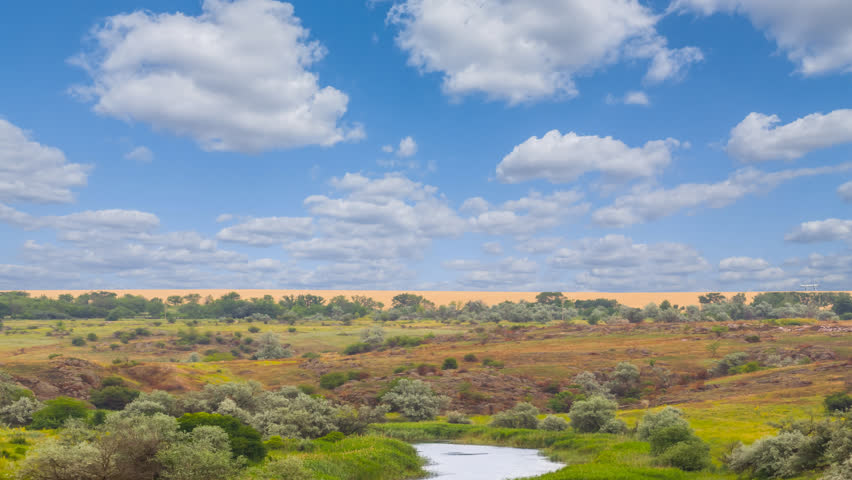 small river flow among a prairie under blue cloudy sky time lapse scene