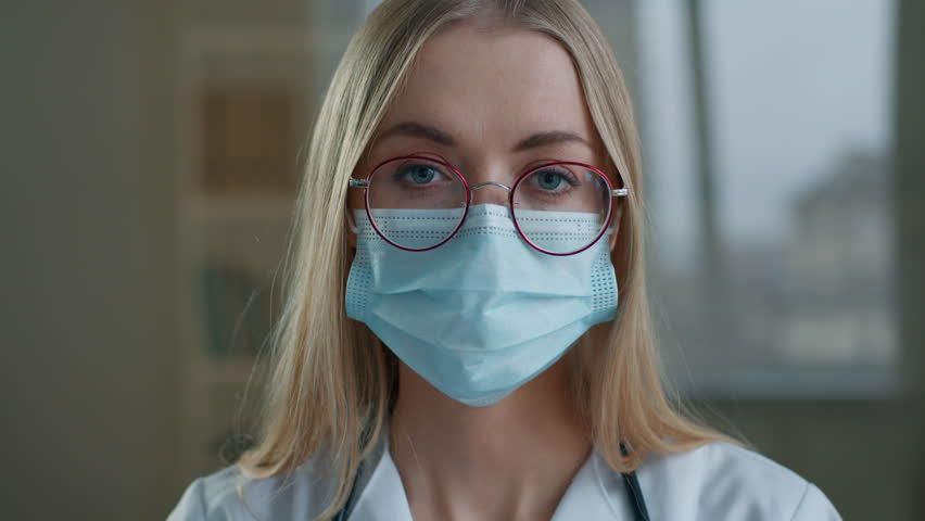 Close-up woman doctor showing vaccine injection bottle in laboratory female scientist nurse girl in medical mask looking at camera holding covid19 coronavirus drug remedy vaccination medicine health