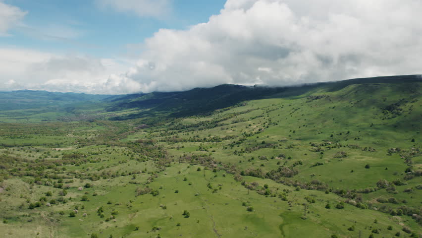 Aerial view of green hills with moving cloud shadows