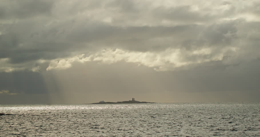 Sunbeams over a small island near the Atlantic Ocean Road, Norway dramatic storm clouds and shimmering sea