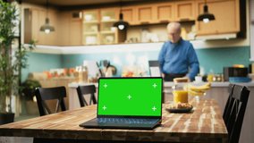 Green screen laptop with elderly woman sitting at the breakfast table, enjoying coffee, toast and pastry for a cozy morning routine. Aged person looks at a device, relaxing indoors. Camera A. - Powered by Shutterstock - Get 15% off with code: PIKWIZARD15