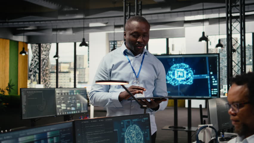 Smiling IT staff members in office using AI to optimize company systems performance. Happy colleagues in startup office use artificial intelligence technology to automate tasks, camera A