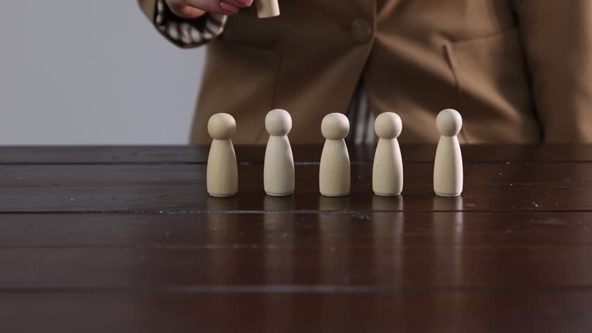 Woman putting human figures onto wooden table, closeup. Camera moving in